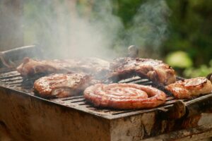 A sizzling BBQ grill with meat and sausages smoking outdoors, perfect for summer cookouts.